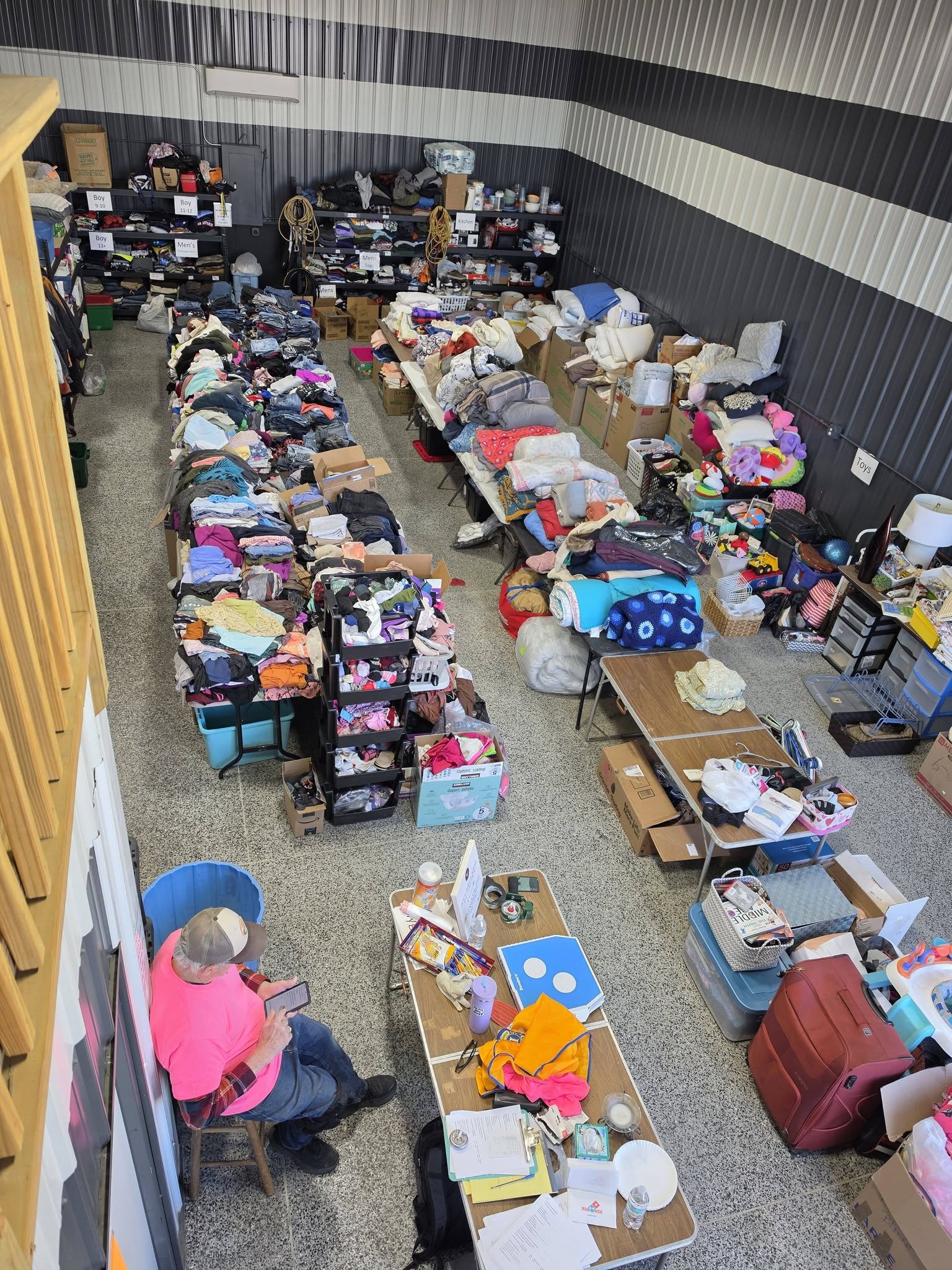 Inside the ND Lions Emergency Relief center at Storage Kings Unit #4 — sorted clothing, household basics, and a volunteer at the intake desk
